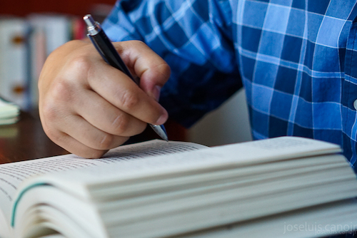 a hand with a pen over a line in a book