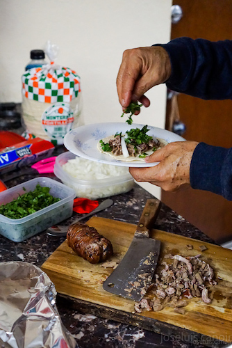 hands putting cilantro on tacos