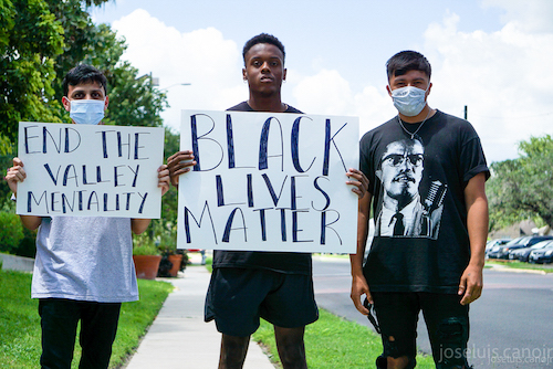 three individuals holding two signs